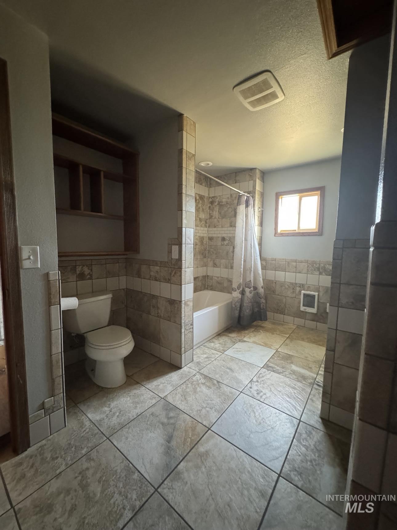40336 Sr 129 Anatone, WA 99401 - Photo 12 of 29 Full bath featuring tile walls, wainscoting, shower / bath combo with shower curtain, and a textured ceiling