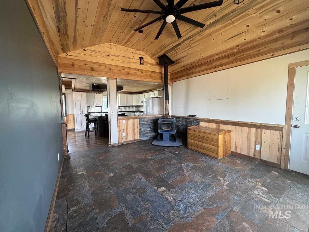 40336 Sr 129 Anatone, WA 99401 - Photo 7 of 29 Unfurnished living room with vaulted ceiling, wood walls, a ceiling fan, wooden ceiling, and wainscoting