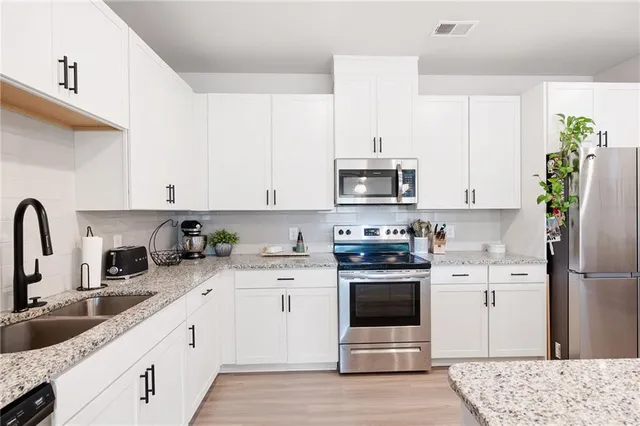 a kitchen with stainless steel appliances granite countertop a stove a sink dishwasher and a refrigerator