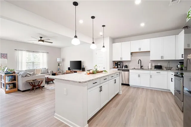 a kitchen that has a lot of cabinets a sink dishwasher and a stove with wooden floor