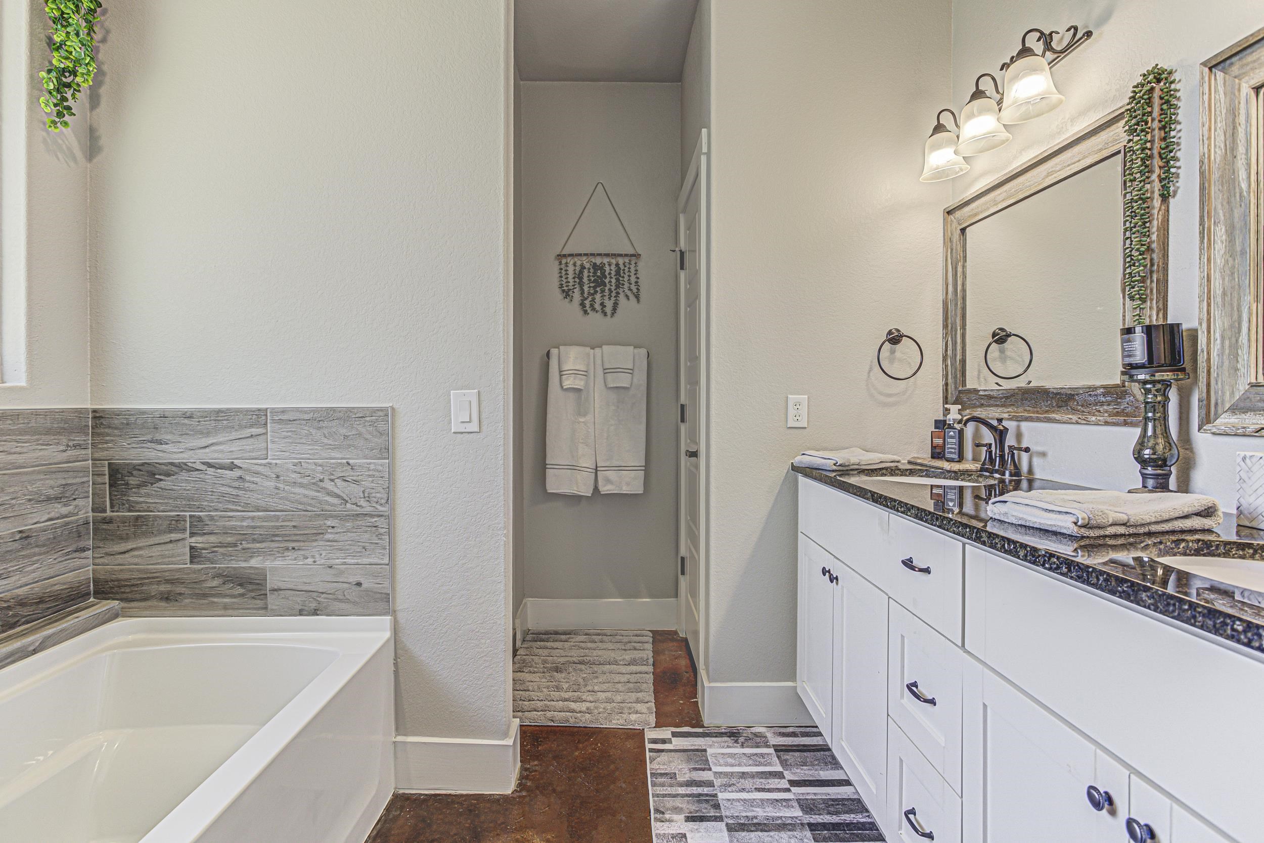 433 Dove Trail Bertram, TX 78605 - Photo 23 of 30 a bathroom with a granite countertop sink mirror and a bathtub