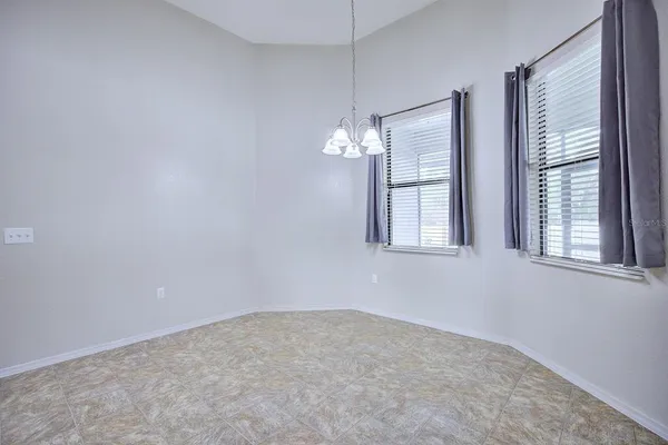 en empty room with windows and chandelier fan