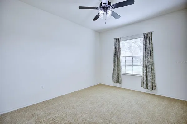 an empty room with windows and fan