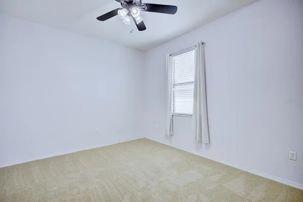 an empty room with a chandelier fan and windows