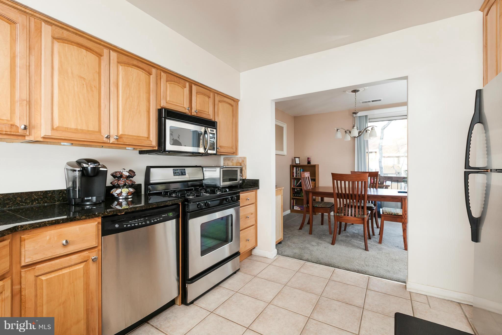 16 Cross Keys Road, Unit 16D Baltimore, MD 21210 - Photo 10 of 29 a kitchen with granite countertop a stove top oven dining table cabinets and a window