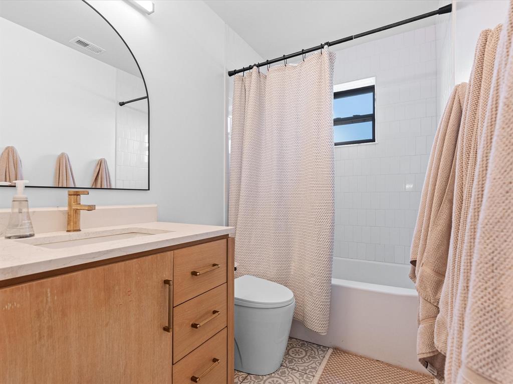 946 Burke Road Gunter, TX 75058 - Photo 19 of 38 a bathroom with a granite countertop sink toilet a mirror and shower