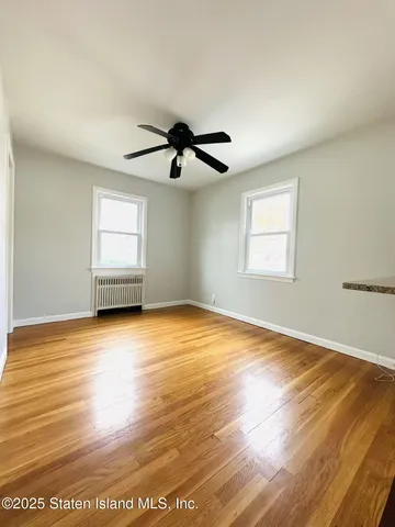 a view of empty room with wooden floor and window