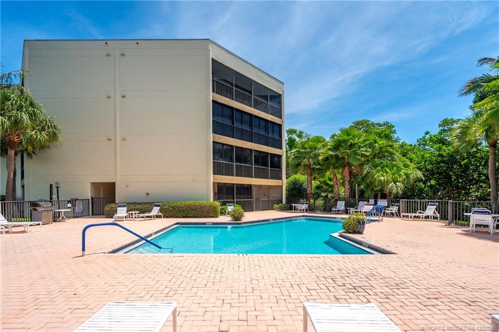 221 Northeast Plantation Road, Unit 407 Stuart, FL 34996 - Photo 10 of 42 a view of swimming pool with outdoor seating and a palm tree