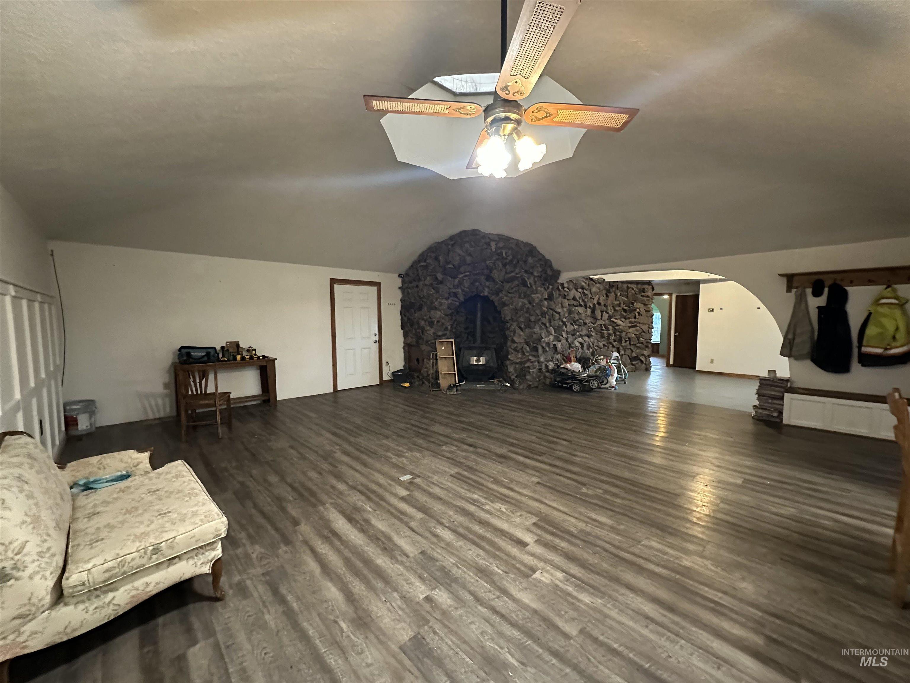 5860 Akron Road New Plymouth, ID 83655 - Photo 12 of 33 Unfurnished living room featuring dark wood-style floors, arched walkways, ceiling fan, and vaulted ceiling