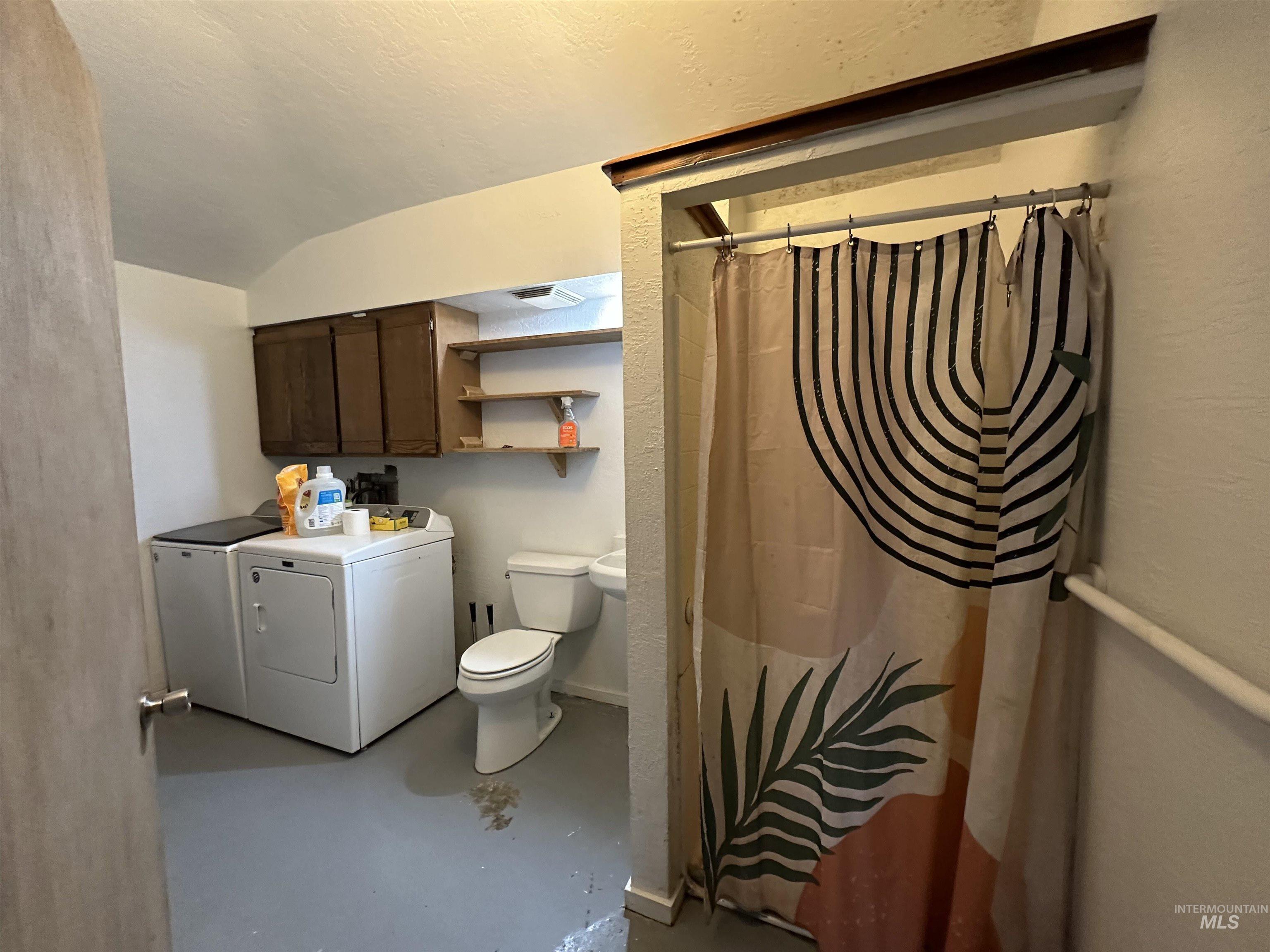5860 Akron Road New Plymouth, ID 83655 - Photo 20 of 33 Full bathroom with finished concrete floors, a shower with shower curtain, independent washer and dryer, and a textured ceiling