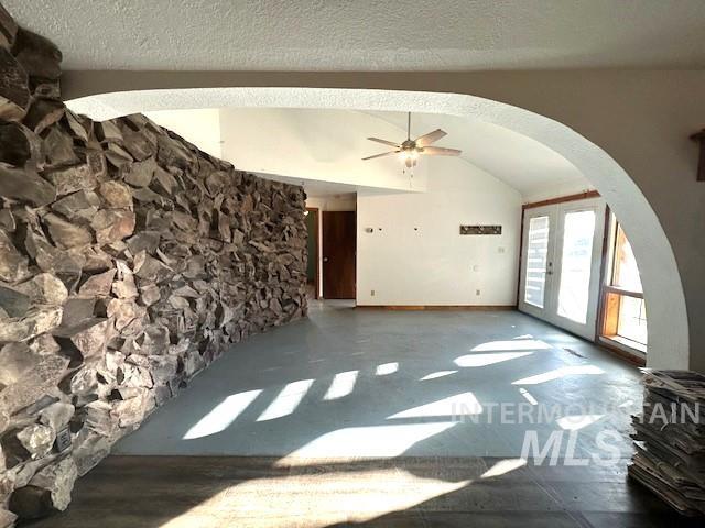 5860 Akron Road New Plymouth, ID 83655 - Photo 2 of 33 Unfurnished living room with arched walkways, french doors, a ceiling fan, a textured ceiling, and vaulted ceiling