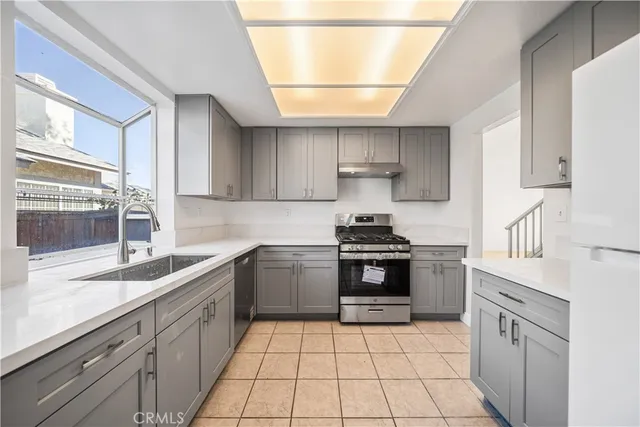 a kitchen with a sink a stove top oven and cabinets