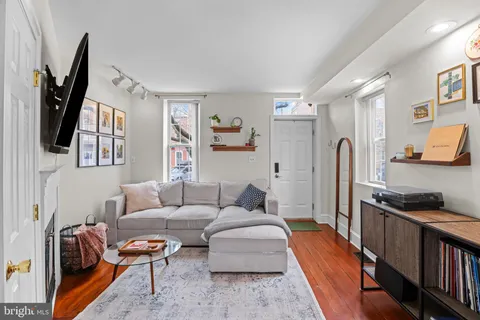 a living room with furniture a flat screen tv and a refrigerator