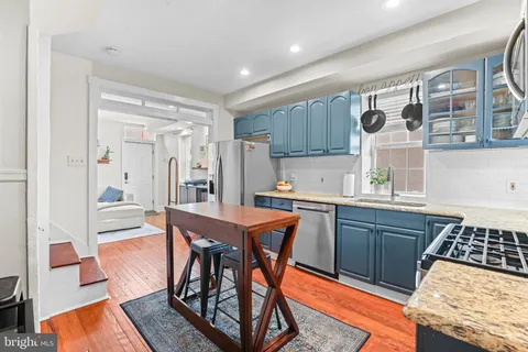 a kitchen with stainless steel appliances granite countertop a stove a sink dishwasher and a refrigerator with wooden cabinets
