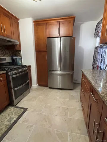 a kitchen with granite countertop a refrigerator and a stove top oven