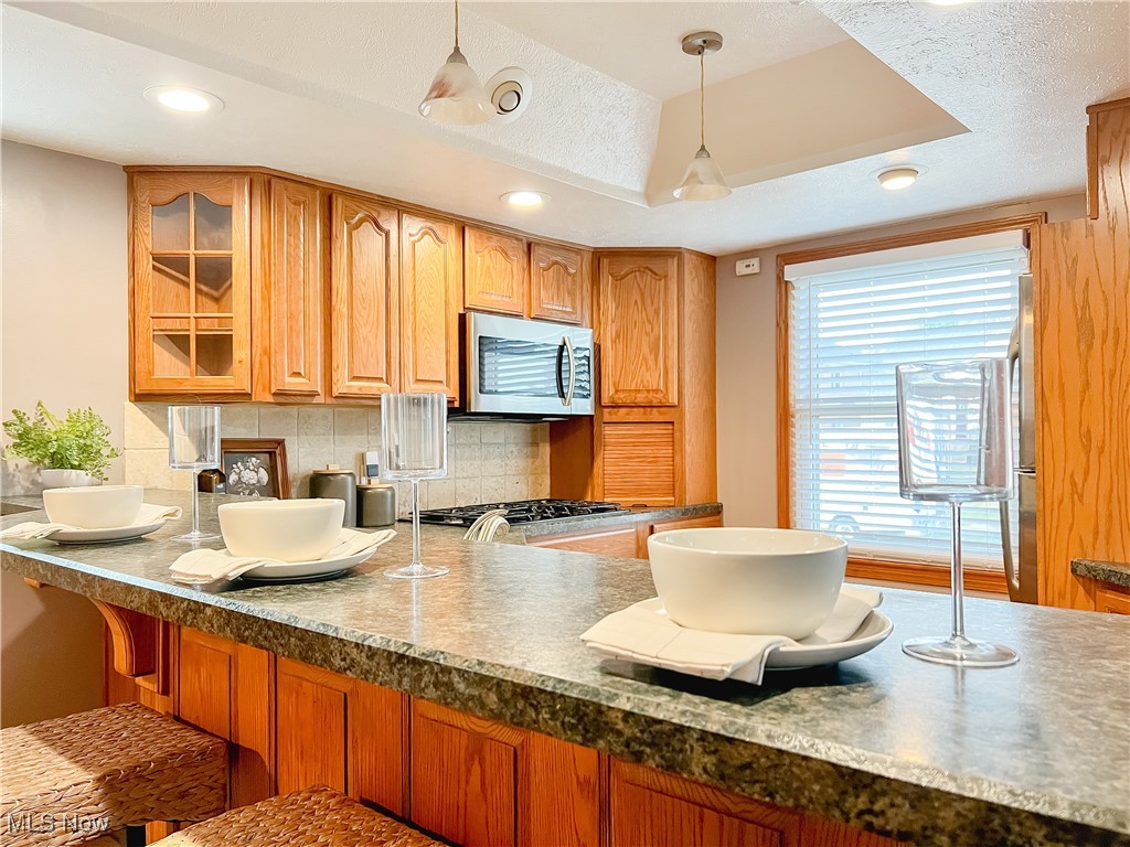 6403 Kenneth Avenue Parma, OH 44129 - Photo 5 of 20 Kitchen with tasteful backsplash, hanging light fixtures, a raised ceiling, stainless steel microwave, and recessed lighting