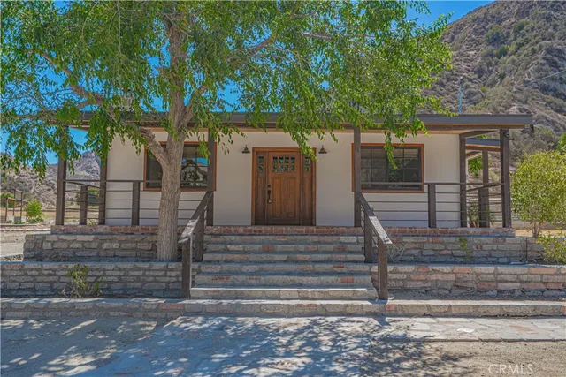 a front view of a house with a tree