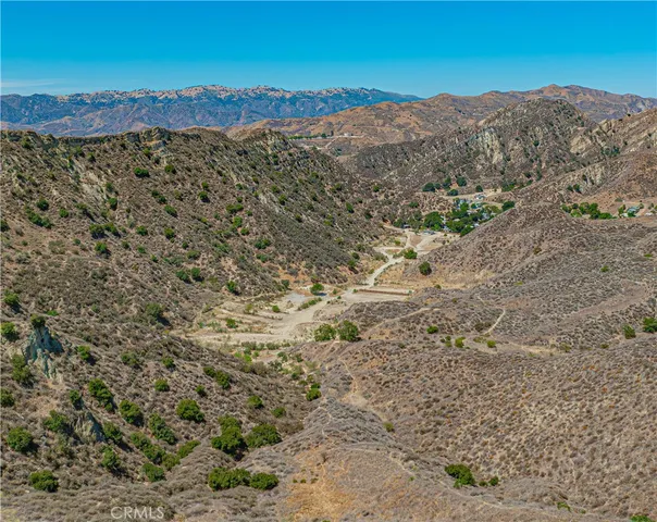 a view of a dry field with mountains in the background