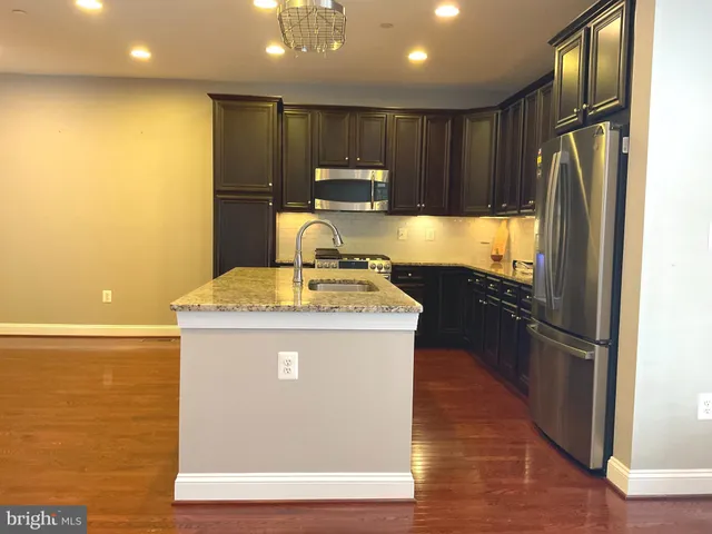 a kitchen with stainless steel appliances granite countertop a refrigerator a sink and a stove