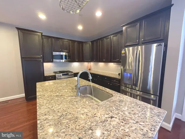 a kitchen with kitchen island a counter top space cabinets and stainless steel appliances