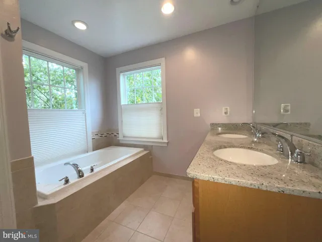 a bathroom with a granite countertop sink a bathtub and window