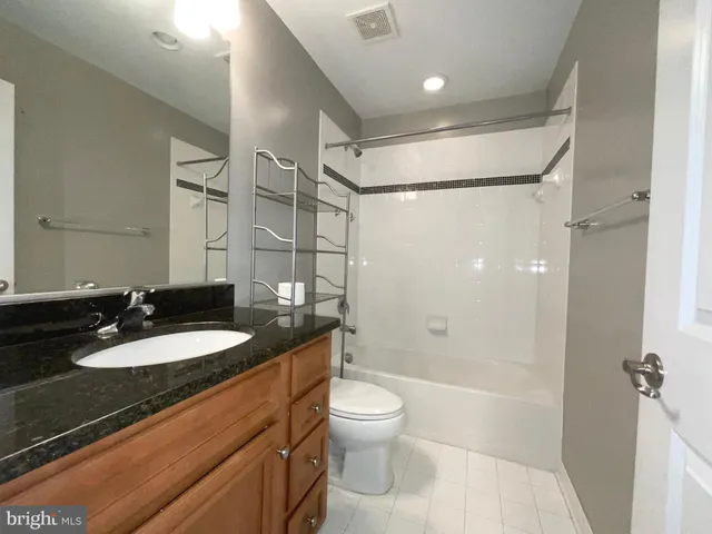 a bathroom with a granite countertop sink toilet a mirror and shower