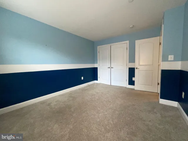 a view of an empty room with kitchen and window