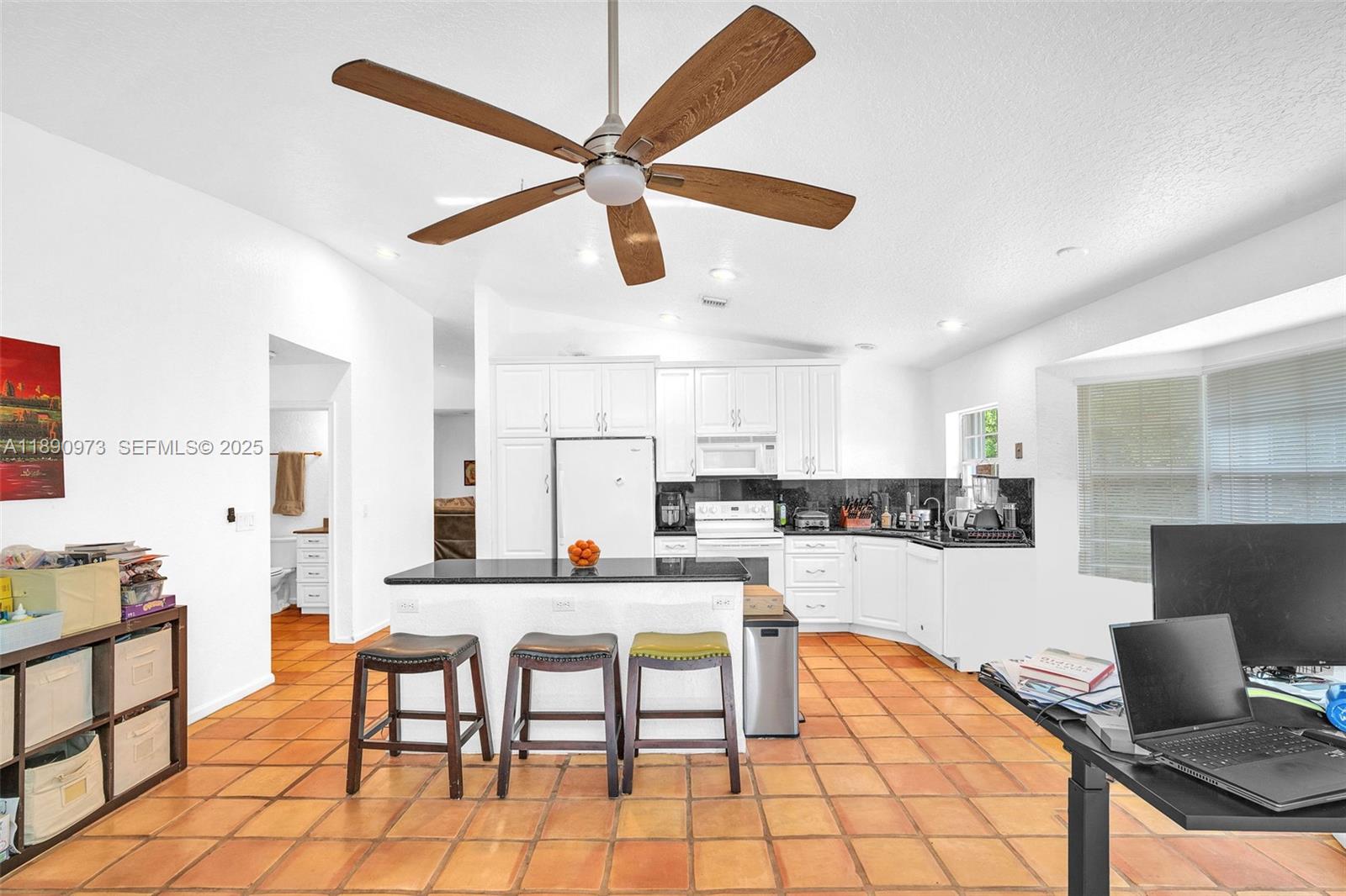 9690 Northwest 39th Street Cooper City, FL 33024 - Photo 13 of 30 a kitchen with stainless steel appliances kitchen island granite countertop a dining table chairs and a refrigerator
