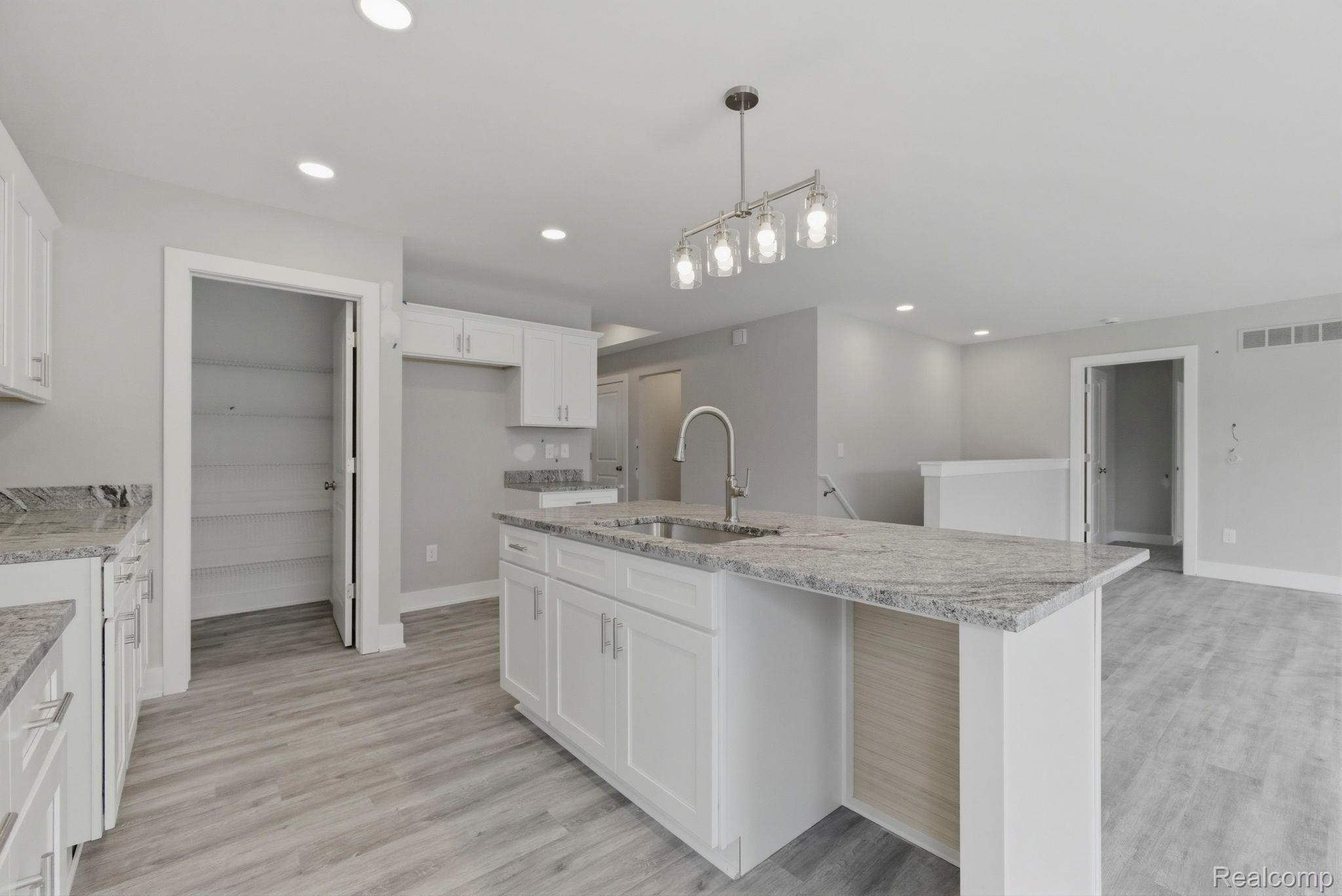 2281 Baltimore Davison, MI 48423 - Photo 9 of 26 Kitchen featuring white cabinets, light stone countertops, an island with sink, and light wood-style flooring