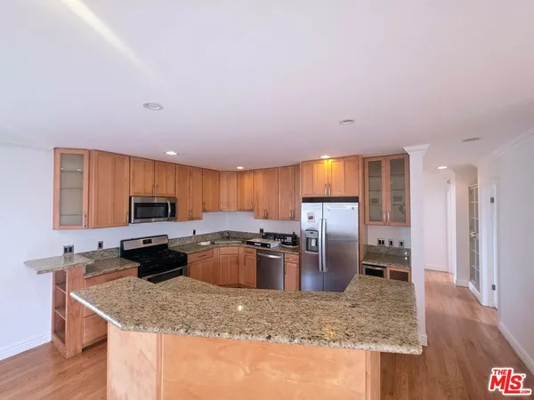 a kitchen with kitchen island granite countertop a stove sink and cabinets