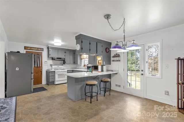 a dining room with stainless steel appliances kitchen island granite countertop a refrigerator oven a sink dishwasher and a dining table with the view of kitchen
