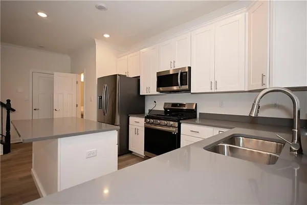a kitchen that has a sink stainless steel appliances a refrigerator and cabinets