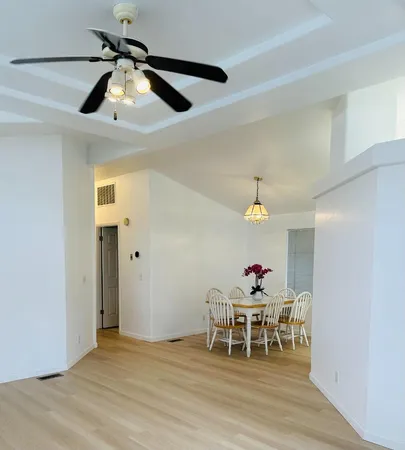 a dining room with wooden floor a chandelier a wooden table and chairs