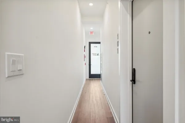 a view of a hallway with wooden floor and a bathroom