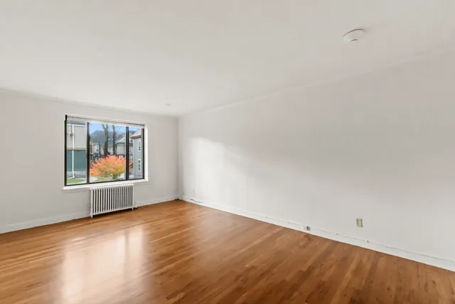 an empty room with wooden floor and window
