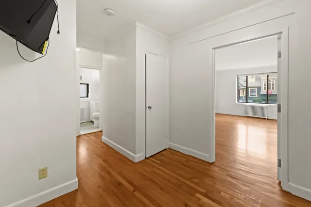 a view of empty room with wooden floor and fan