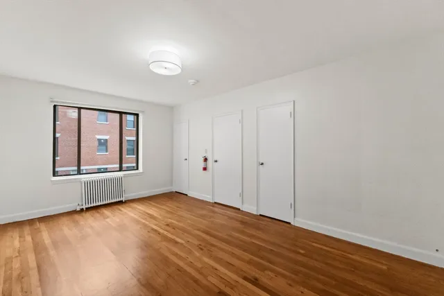 a view of an empty room with window and wooden floor