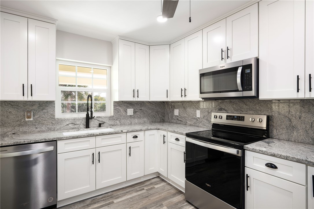 1180 Reef Road, Unit A20 Vero Beach, FL 32963 - Photo 11 of 32 a kitchen with granite countertop white cabinets appliances a sink and a window