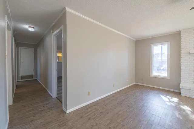 a view of hallway with window and wooden floor