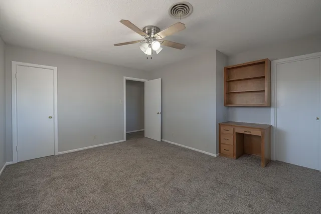 a view of an empty room with a chandelier fan