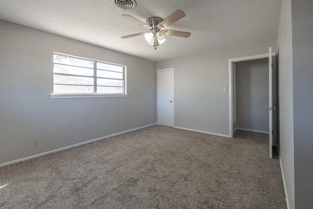 an empty room with windows and ceiling fan