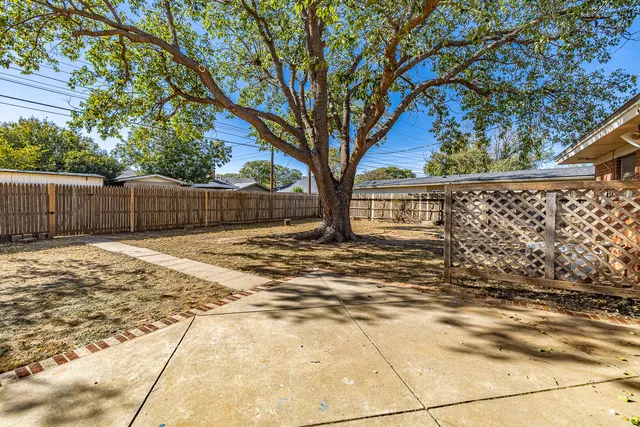 a view of backyard of house with wooden fence