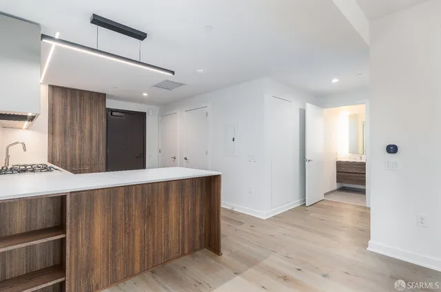 a view of a kitchen with refrigerator and wooden floor