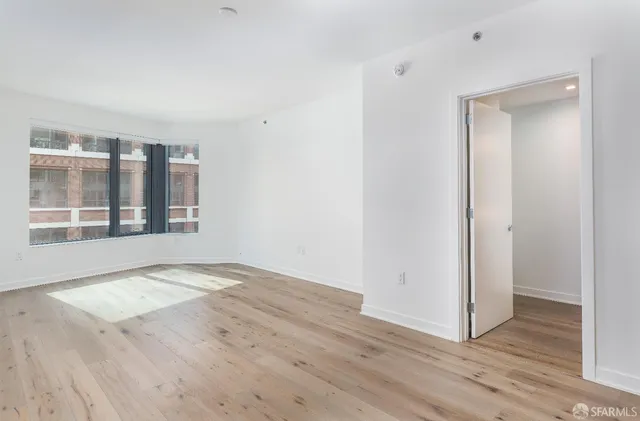 a view of an empty room with wooden floor and a window