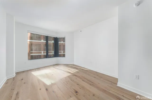 a view of an empty room with a window and wooden floor