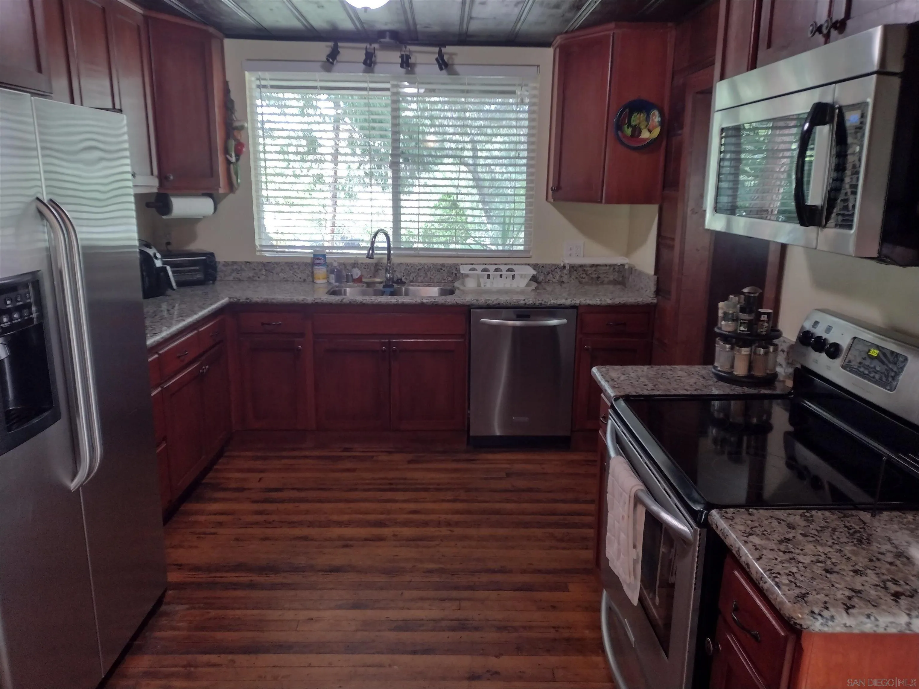 17661 Lyons Valley Road Jamul, CA 91935 - Photo 33 of 50 a kitchen with granite countertop wooden cabinets a sink and dishwasher
