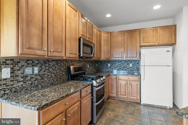 a kitchen with stainless steel appliances granite countertop a stove a sink and a microwave
