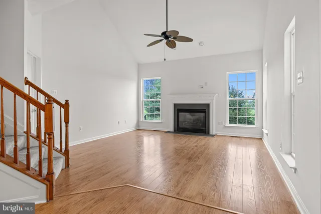 a view of an empty room with wooden floor fireplace and a window