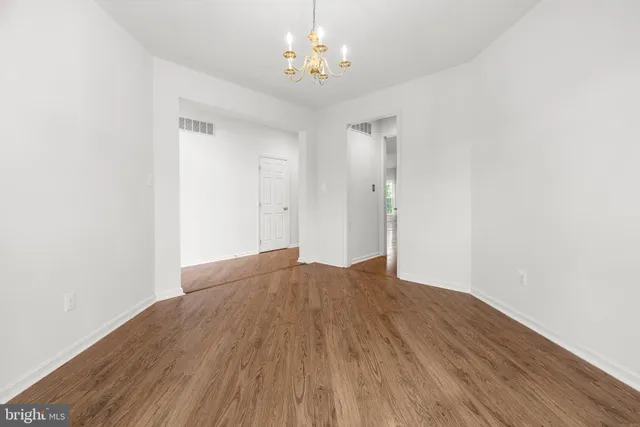 a view of empty room with wooden floor and chandelier