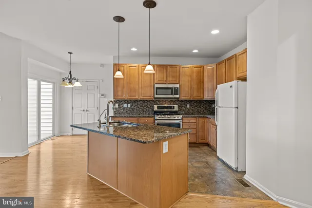 a kitchen with stainless steel appliances granite countertop a refrigerator a stove a sink and a refrigerator